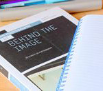 Front cover of Behind the Image with notebook next to it