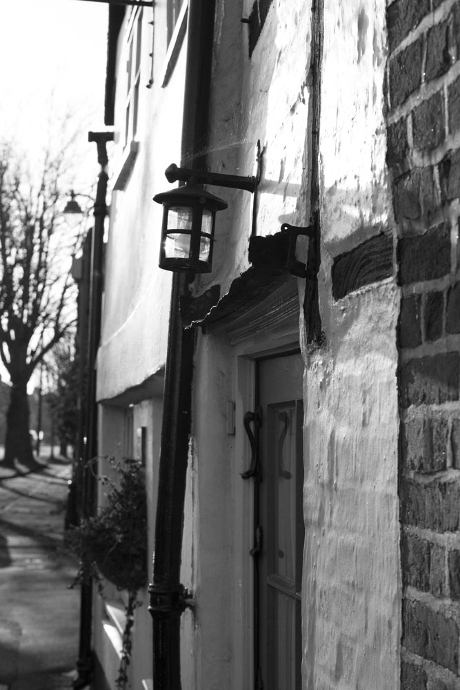 Lamp over a small doorway in a listed building in black and white