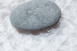 A smooth flat grey pebble on bubblewrap