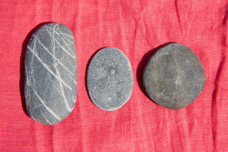 Three flat pebbles on red linen