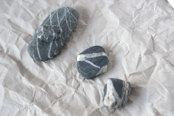 Four grey and white stones placed on crinkled grey paper