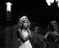 Black and white photograph of two girls one with a candy cigarette